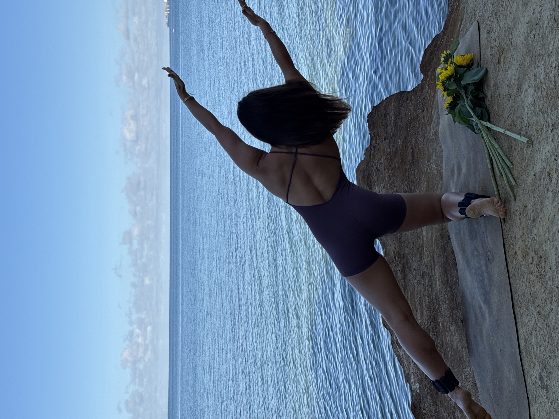 Mon balancing with one leg extended above the ocean